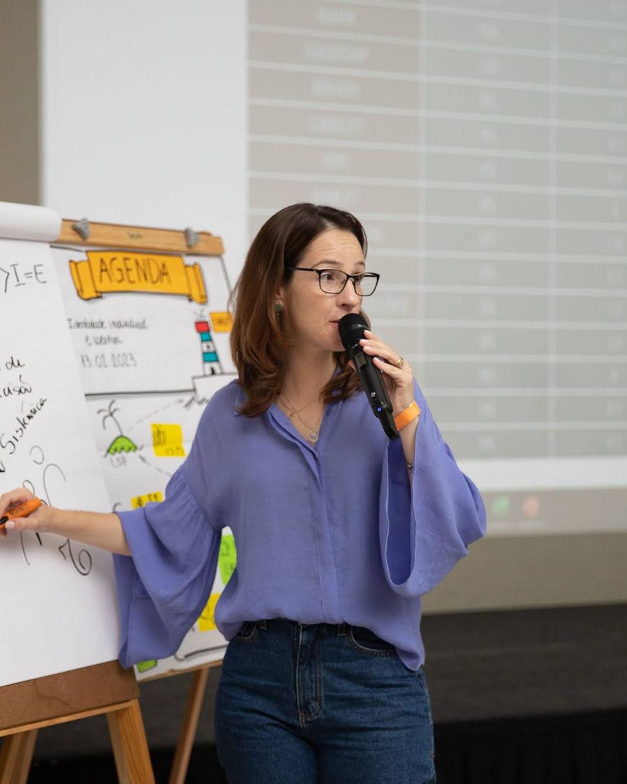 Natália explicando um modelo no flipchart, com microfone
